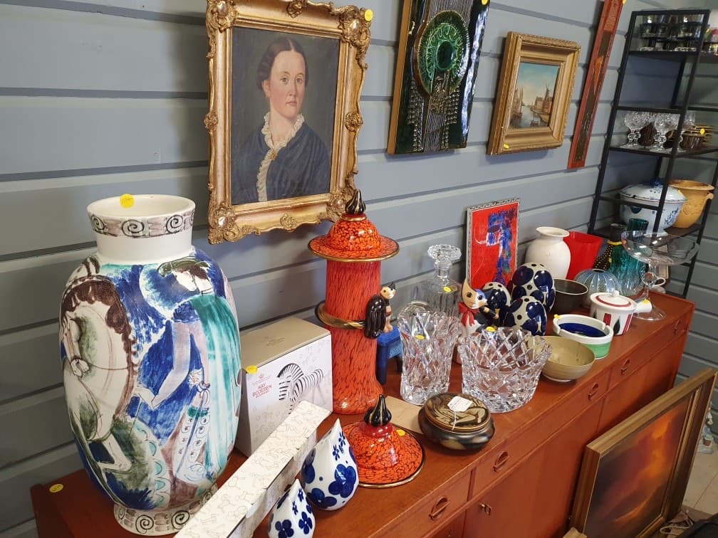 Skänk med konstglas i orange och blått, kristallskålar, karaffer och oljemålningar i guldramar